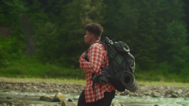 トレッキングで風光明媚な山の自然を楽しむハンサムな黒人男性バックパッカーの肖像画 — ストック動画