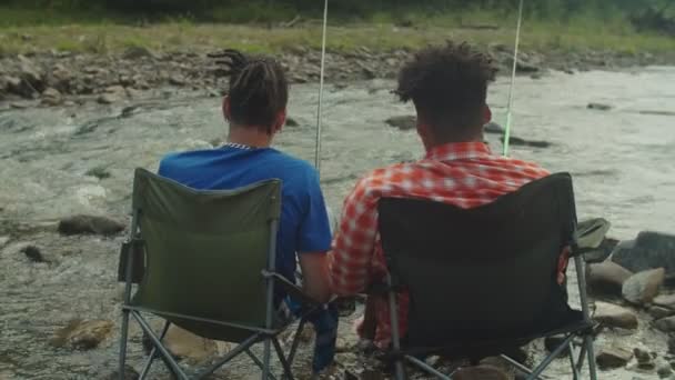 Rear view of multiethnic men with fishing rods angling in mountain river — Stock Video