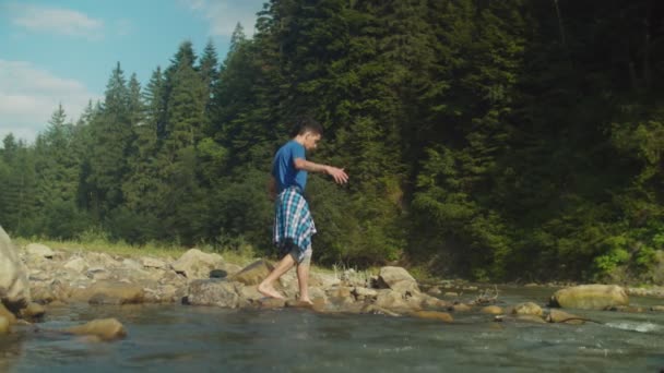 Handsome arab male tourist barefoot crossing through mountain river on trek — Stock Video