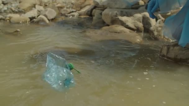 Close-up de mão ambientalista pegando garrafas de plástico desperdiçadas do rio — Vídeo de Stock