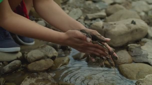 Κοντινό πλάνο γυναικείων χεριών λασπωμένων με λάσπη βιομηχανικών αποβλήτων στον ορεινό ποταμό — Αρχείο Βίντεο