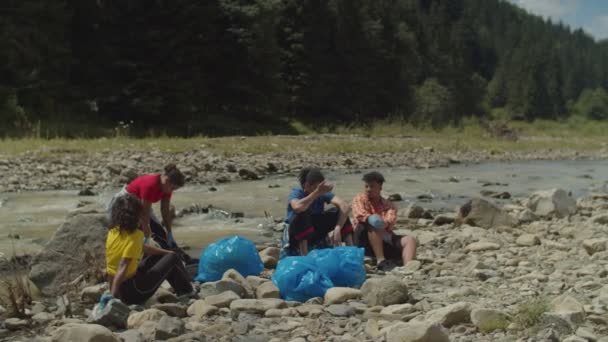 Zmęczeni wielorasowi aktywiści ekologiczni odpoczywający po udanym oczyszczeniu środowiska w górach — Wideo stockowe