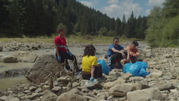 Környezetbarát, kimerült, többnemzetiségű emberek portréja, akik a környezet megtisztítása után pihennek — Stock videók