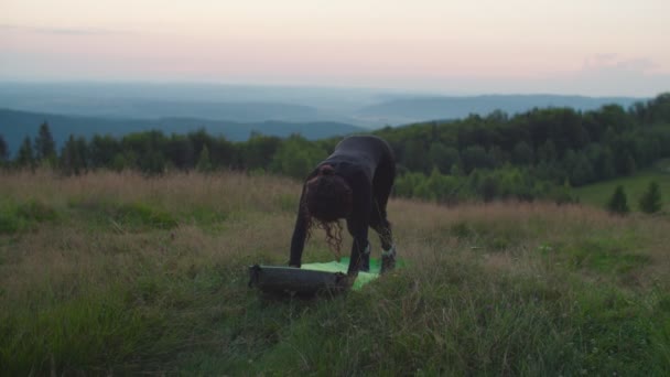 Slim flexible deportivo ajuste africano americano hembra haciendo hacia abajo mirando perro pose en las montañas al amanecer. — Vídeos de Stock