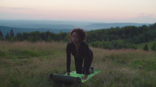 Şafak vakti dağ tepesinde yoga yapan çekici, formda bir zenci kadın. — Stok video