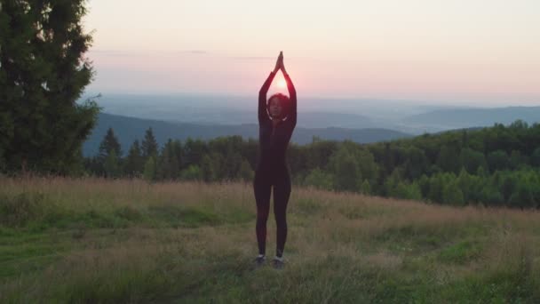 Ontspannen mooie sportieve fit Afrikaanse Amerikaanse vrouw doen yoga zon begroeting poseren in de bergen bij zonsopgang. — Stockvideo