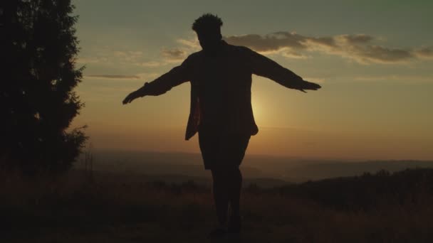 Silhouette aktív férfi áll kiegyensúlyozó, karate gyerek jóga póz a hegy tetején naplementekor — Stock videók