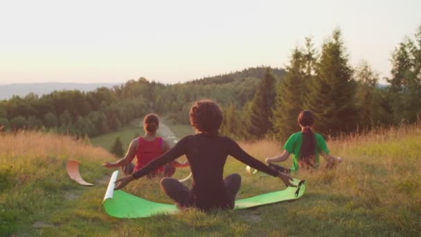 Achteraanzicht van vreedzame sportieve fitness multiraciale vrouwen mediteren, doen zon begroeting yoga pose bij dageraad — Stockvideo