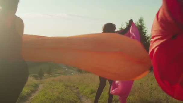 Gente multiétnica diversa positiva inflando sofás de aire coloridos en la cima de la montaña al amanecer — Vídeo de stock