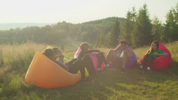 Positivo feliz diversos turistas multiétnicos relajarse en sofás de aire en la cima de la montaña al amanecer — Vídeos de Stock