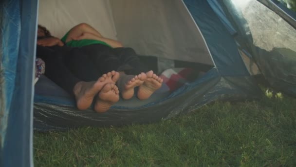 Zbliżenie dwóch par żeńskich nóg wystających z namiotu kempingowego podczas górskich wędrówek — Wideo stockowe