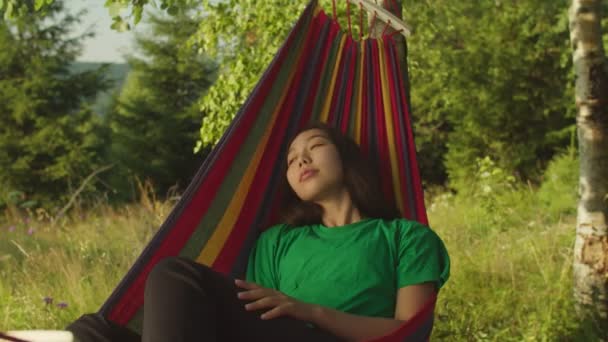 Charmig fridfull asiatisk kvinna resenär i hängmatta njuter av fritid i bergen under vandringen — Stockvideo