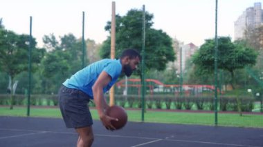 Side view of sporty African American man basketball player driving to hoop, scoring two points with layup shot after assist from teammate while multi ethnic athletes playing streetball game on court