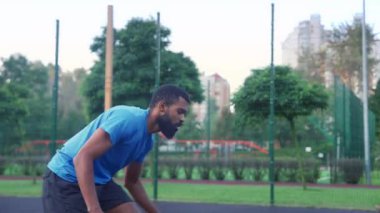 Active sporty fit black male basketball player driving to the hoop, receiving pass from teammate and failing to score points after layup shot while multiracial athletes playing game on outdoor court