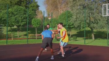 Positive sporty fit multiracial male basketball players celebrating scoring points with back bump, expressing happiness and cheerful mood while multi ethnic sports teams playing streetball on court.