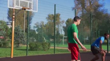 Aktif formda sporcu erkek basketbol oyuncusu, dışarıda sahalarda sokak oyunları oynayan çok ırklı sporcular, turnike atışlarıyla iki puan alarak Afrikalı Amerikalı takım arkadaşından yardım alıyor..