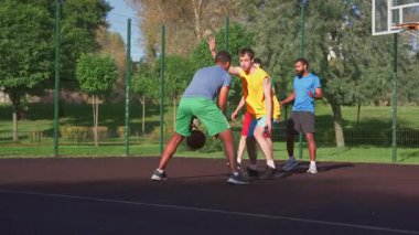 Becerikli sporcu basketbol formundaki savunma oyuncusu Afrika kökenli Amerikan forvetinden top çalıyor, çok ırklı spor takımları açık sahada sokak basketbolu oynarken potaya gidiyor..