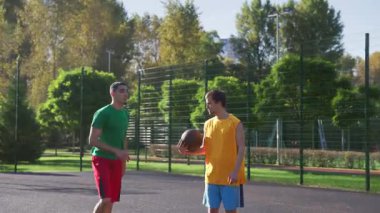 Atletik Afrikalı Amerikalı erkek basketbolcu takım arkadaşından pas alıyor, tek elle potaya gidiyor ve tek elle smaç basıyor aynı zamanda sahada çok ırklı spor takımları oynuyor.