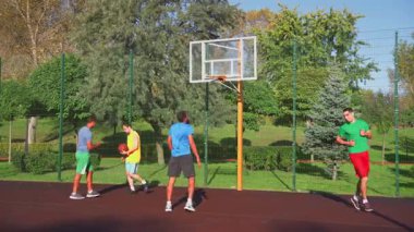 Neşeli spor, çok ırklı erkek basketbolcuların zaferini beşlik bir jestle kutlarken, çok ırklı spor takımları sokak oyunu oynarken mutluluk ve birliği ifade ederek kutluyor..