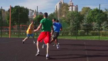 Aktif sportif formda basketbol oyuncusu Afrika kökenli Amerikalı erkek takım arkadaşına başarılı bir asist yaparak, açık sahada çok ırklı spor takımları oynarken turnike atışlarıyla puan toplamaya yardım ediyor.