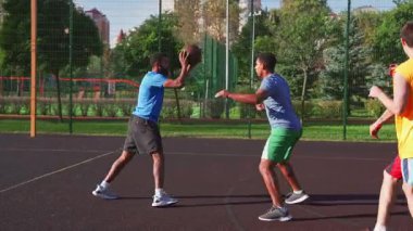 Aktif spor formundaki Afro-Amerikan erkek basketbolcu potaya gidiyor, saha golünü kaçırıyor, hücum ribaund ve sayı kazandırıyor çok ırklı sporcular kortta sokak basketbolu oynarken.