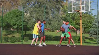 Yetenekli Afrikalı Amerikalı basketbolcu, dönen ve rakip defans oyuncusunun etrafında dönen ve çok ırklı sporcular kortta sokak basketbolu oynarken turnikeyle sayı yapan.