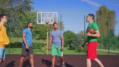 Motivasyonlu atletik formda çeşitli etnik çeşitlilikte basketbol oyuncuları topa beşlik çakıyor, birlik, takım ruhu, iyi sportmenlik ve açık sahadaki sokak topu maçından önce hazırlık gösteriyor..