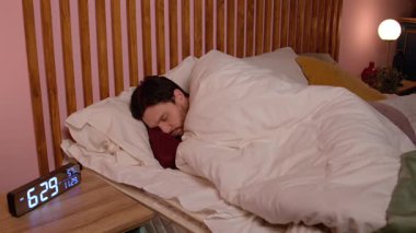 Dinlenmiş, sakallı, orta yaşlı, pijamalı yakışıklı bir adam. Alarmlı saat yüzüğüyle uyanıyor ve esniyor. Evde iyi bir uyku çektikten sonra yenilenme ve gençleşme hissi veriyor..