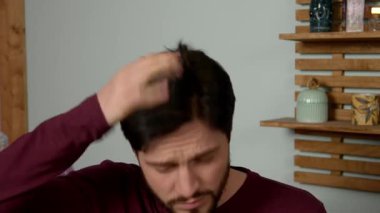 Çekici, sakallı, orta yaşlı bir adam aynaya bakıyor kepek sorunlarını öğreniyor, kafasını gevşeklikten ve kaşıntıdan temizliyor, banyoda asabiyet ve endişelerini dile getiriyor..