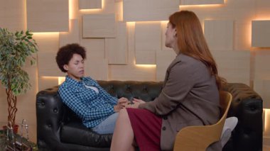 Orta yaşlı kadın psikoterapist hipnozdan dolayı stresli siyah bir kadını uyandırıyor endişeli bir hastayı teselli ederken aynı zamanda hipnoterapi sırasında profesyonel psikolojik yardım sağlıyor.