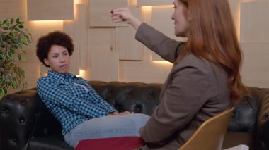 Olgun kadın psikolog, dikkat çekmek ve psikolojik bozukluğun tedavisinde önerilebilirliği artırmak için sarkaç kullanan güzel Afrikalı Amerikalı kadın hastayı hipnotize ediyor..