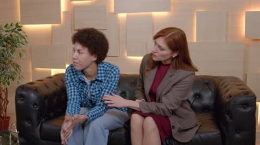 Olgun kadın ruh sağlığı uzmanının koltuğunda oturması, depresif Afrikalı Amerikalı kadın hastayı teselli etmesi, psikoterapi seansı sırasında anlayış, ilgi ve destek göstermesi..