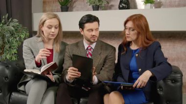 Dijital tabletle başarılı sakallı erkek takım lideri ve çeşitli kadın meslektaşları iş konularını ve finansal verileri tartışıyor, ofiste strateji planlıyor.