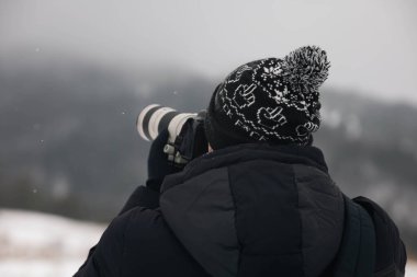Fotoğrafçı, Karpatlar 'ın Dağları' nı arkadan çekerken, Karpatlar 'ın manzaralı dağlarını çekerken kendine özgü bir şapka takan bir fotoğrafçının fotoğrafını çekiyor..