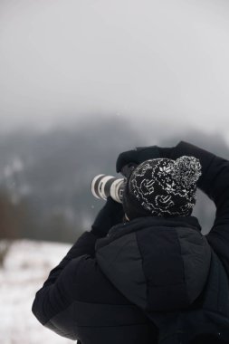 Fotoğrafçı, Karpatlar 'ın Dağları' nı arkadan çekerken, Karpatlar 'ın manzaralı dağlarını çekerken kendine özgü bir şapka takan bir fotoğrafçının fotoğrafını çekiyor..