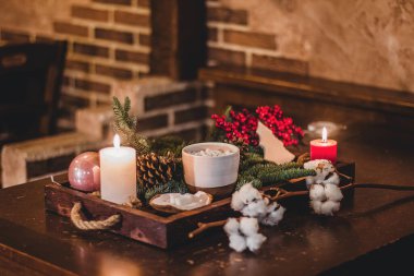 Noel sıcak çikolatası ve küçük şekerlemeler eski seramik bir kupada, ahşap bir arka planda mumlar..