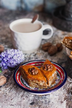Çeşitli baklavalar. Arka planda kahve fincanı olan dekoratif tabakta Türk ramazanı tatlı bir Arap tatlısı. Orta Doğu gıda baklavası, fındık ve bal şurubu.