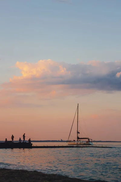 Günbatımına karşı yat sürüyor. Ufuk çizgisi yelkenli ve iki martı olan tatil yaşam tarzı manzarası. Yat turizmi - deniz akşam yürüyüşü. Günbatımında lüks bir yatta romantik bir gezi.
