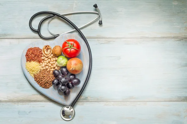 Healthy lifestyle and healthcare concept with food, heart and stethoscope — Stock Photo, Image