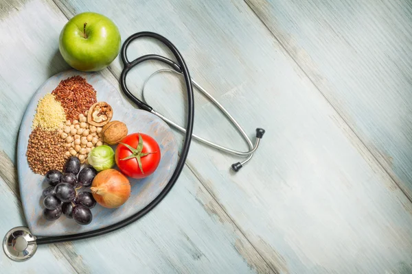 Healthy lifestyle and healthcare concept with food, heart and stethoscope — Stock Photo, Image