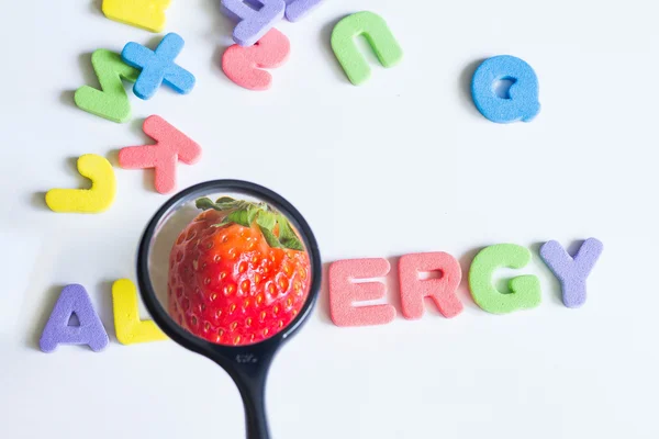 Alergia alimento fresa fruta concepto con letras y lupa —  Fotos de Stock