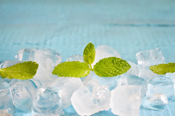 Ice cubes and fresh mint leaves abstract background on blue boards — Stock Photo, Image