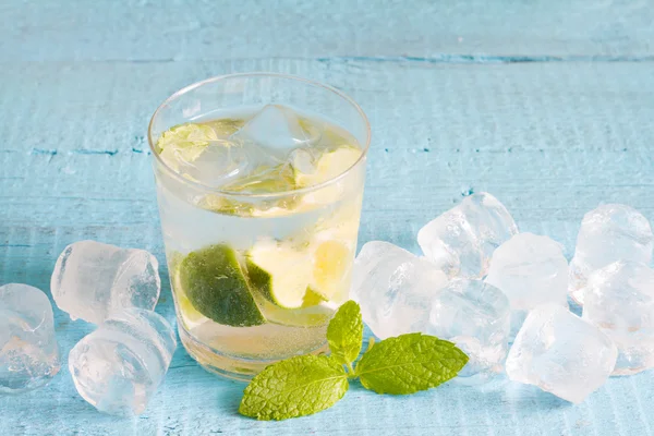 Glas Wasser mit Minze und Eiswürfeln auf blauen Brettern — Stockfoto