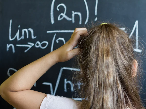 Школьница думает о сложной задаче математики на доске — стоковое фото