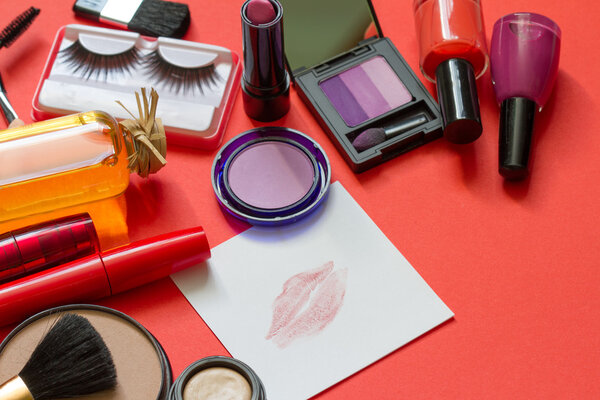 Cosmetics and red lipstick on the paper abstract background concept