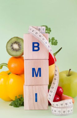  Kelime BMI ahşap bloklardan yapılmış. Meyveler, sebzeler ve mezura, sağlıklı beslenme konsepti 