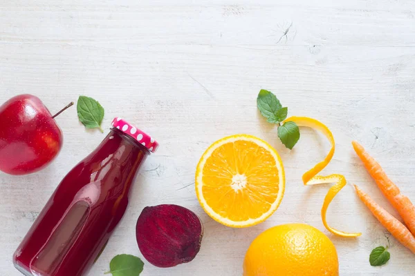 Freshly squeezed juice in glass bottle with composition of vegetables and fruits on light background