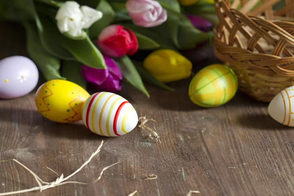 Uova di Pasqua e tulipani su tavola di legno — Foto Stock