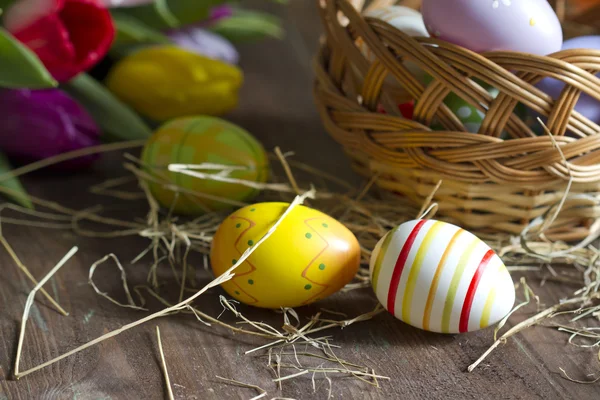 Uova di Pasqua e tulipani su tavola di legno — Foto Stock