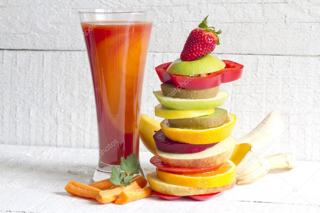 Fresh spring juice and pile of slice fruits and vegetables